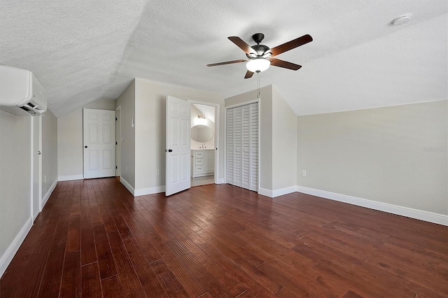 bonus room with a wall mounted air conditioner, a textured ceiling, ceiling fan, dark hardwood / wood-style floors, and lofted ceiling