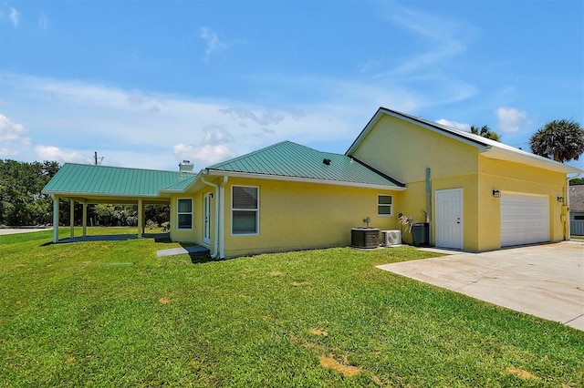 rear view of property featuring central air condition unit, a yard, and a garage