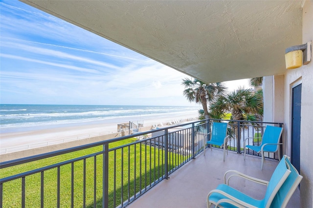 balcony with a water view and a view of the beach