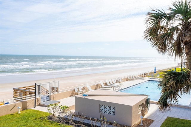 view of pool featuring a water view, a patio, and a beach view