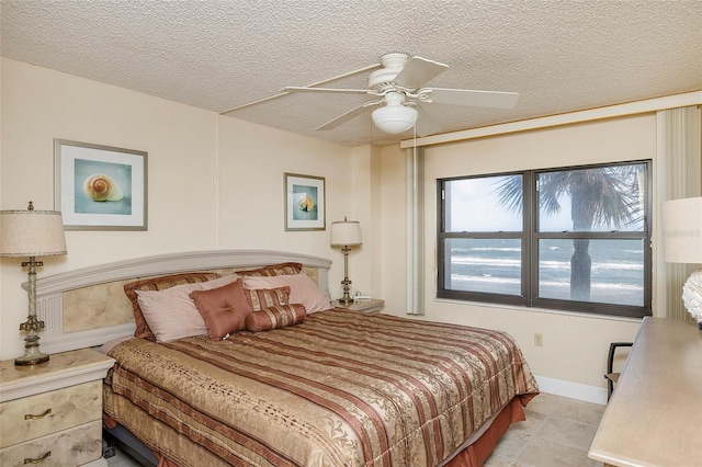 bedroom with ceiling fan, light tile patterned floors, and a textured ceiling