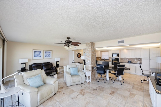 living room with a textured ceiling and ceiling fan