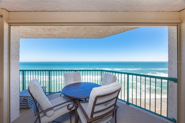 balcony with a water view and a view of the beach