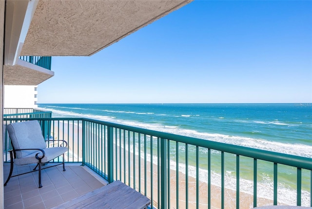 balcony featuring a view of the beach and a water view