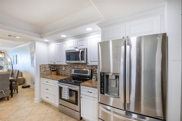 kitchen featuring decorative backsplash, dark stone counters, stainless steel appliances, light tile patterned floors, and white cabinetry