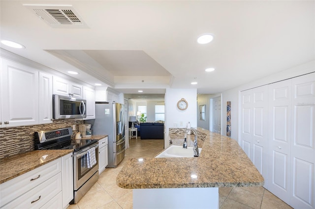 kitchen featuring appliances with stainless steel finishes, a kitchen island with sink, sink, light tile patterned floors, and white cabinets