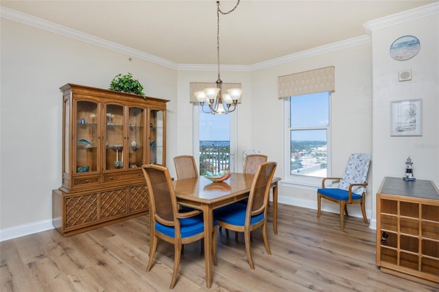 dining room featuring light wood-type flooring, crown molding, and a notable chandelier