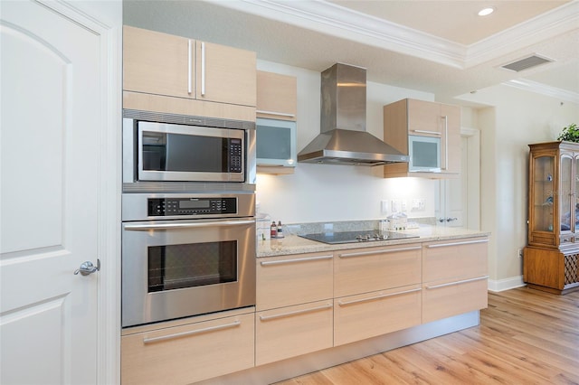 kitchen featuring light brown cabinets, light wood-type flooring, stainless steel appliances, and wall chimney range hood