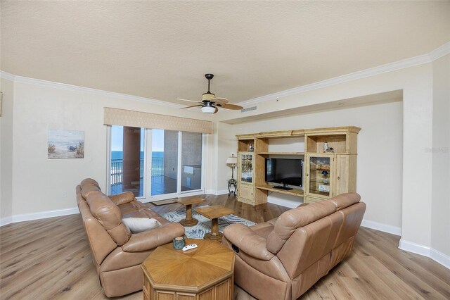 living room featuring ceiling fan, ornamental molding, a textured ceiling, and light wood-type flooring