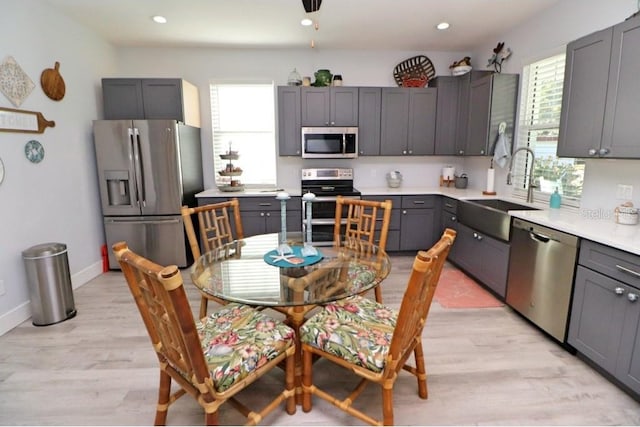 kitchen featuring light wood-type flooring, stainless steel appliances, gray cabinets, and sink