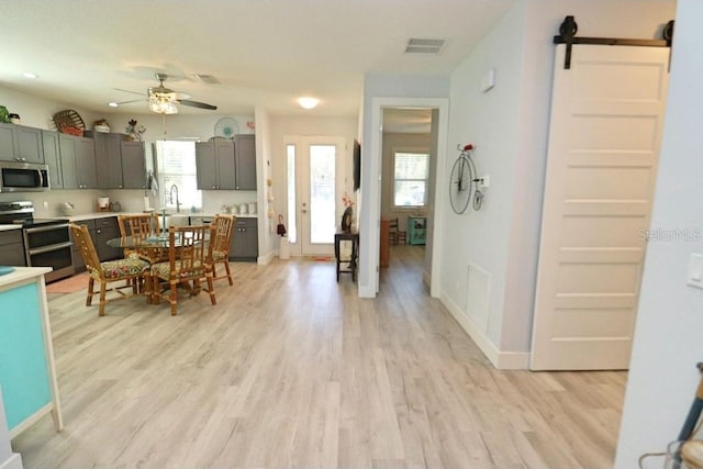 interior space featuring a barn door, ceiling fan, light hardwood / wood-style flooring, and sink