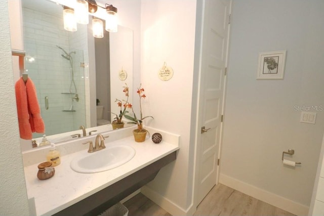 bathroom with hardwood / wood-style floors, a shower with shower door, and sink