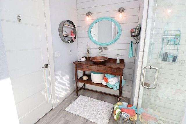 bathroom with sink, a shower with shower door, and hardwood / wood-style flooring