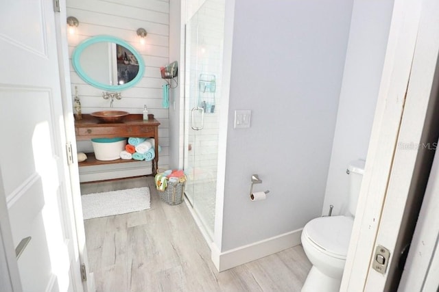 bathroom featuring hardwood / wood-style floors, toilet, a shower with shower door, and sink