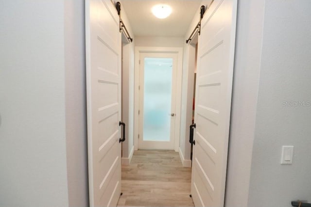 hall with a barn door and light hardwood / wood-style floors