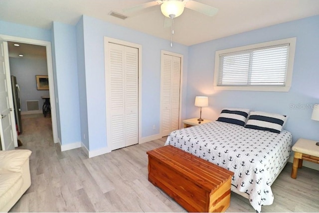 bedroom featuring stainless steel refrigerator, ceiling fan, light hardwood / wood-style flooring, and two closets