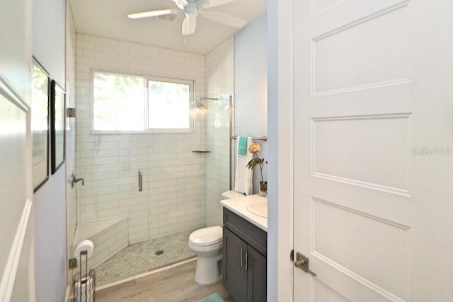 bathroom featuring ceiling fan, wood-type flooring, an enclosed shower, toilet, and vanity