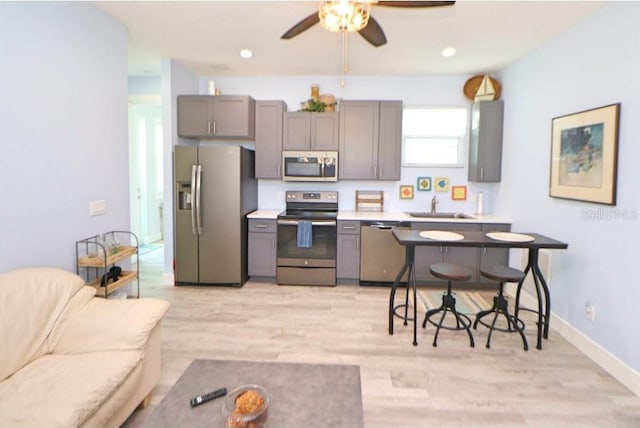 kitchen with ceiling fan, sink, light hardwood / wood-style floors, gray cabinets, and appliances with stainless steel finishes