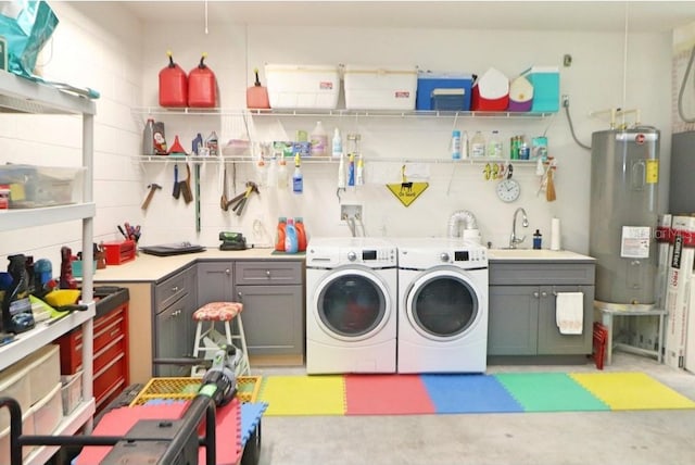 clothes washing area with cabinets, electric water heater, washer and clothes dryer, and sink