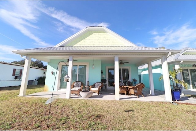 rear view of house featuring ceiling fan, a patio area, and a yard