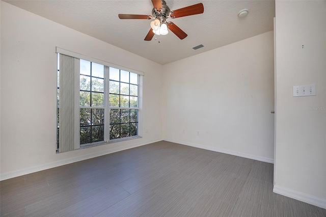 empty room with ceiling fan, dark hardwood / wood-style flooring, and a textured ceiling