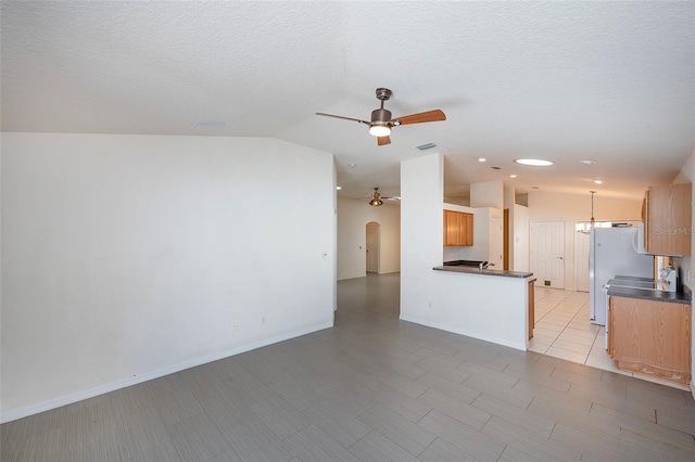 interior space with a textured ceiling, vaulted ceiling, and ceiling fan