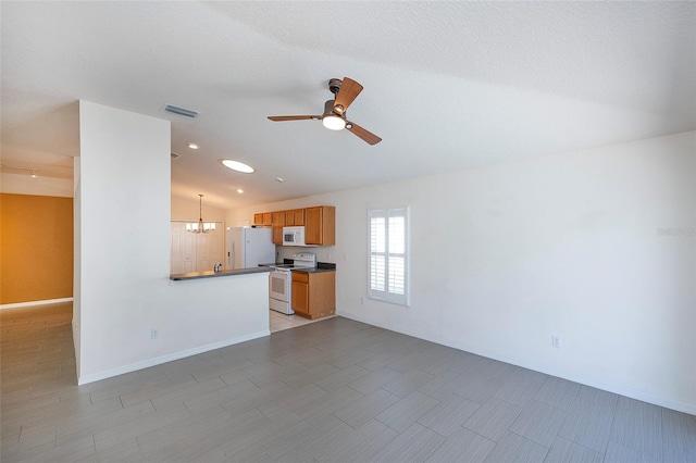 kitchen with ceiling fan with notable chandelier, a textured ceiling, white appliances, vaulted ceiling, and decorative light fixtures