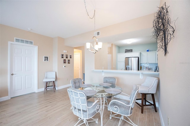 dining space with light hardwood / wood-style floors and a notable chandelier