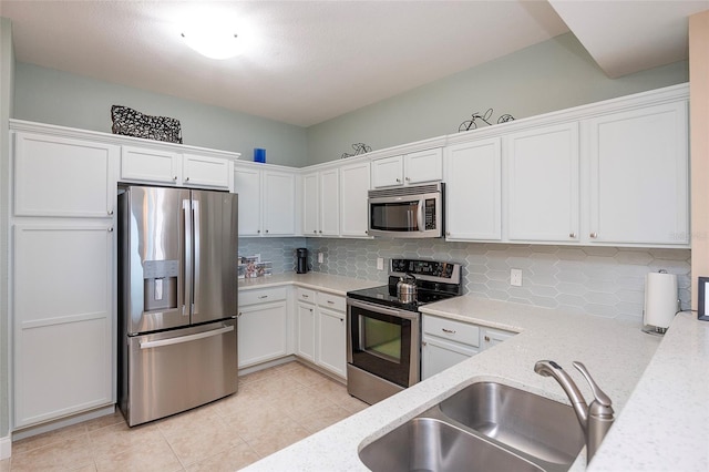 kitchen featuring light stone countertops, sink, backsplash, white cabinets, and appliances with stainless steel finishes