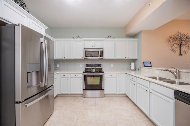 kitchen featuring kitchen peninsula, sink, appliances with stainless steel finishes, tasteful backsplash, and white cabinetry