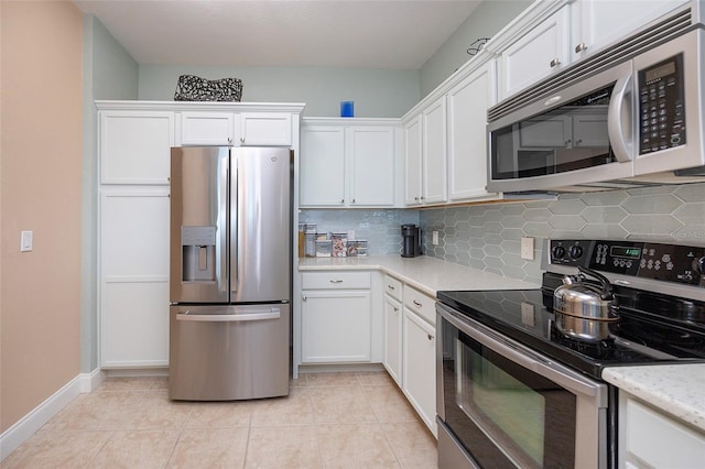 kitchen featuring white cabinetry, light stone counters, backsplash, light tile patterned flooring, and appliances with stainless steel finishes