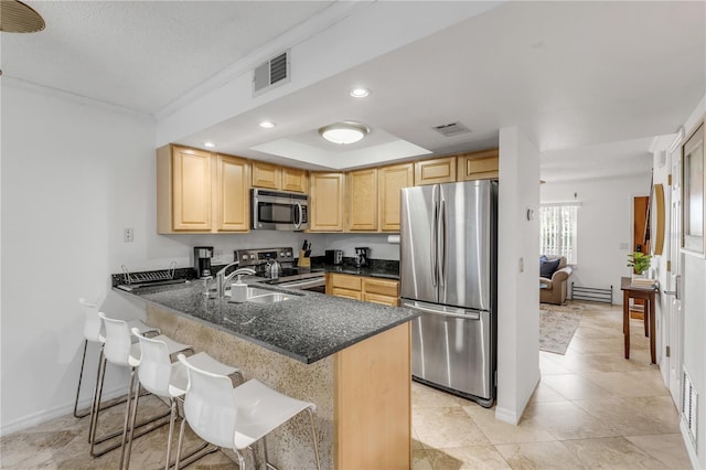 kitchen featuring sink, stainless steel appliances, kitchen peninsula, a breakfast bar area, and light brown cabinetry