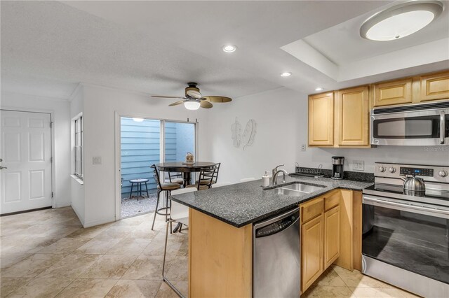 kitchen featuring sink, ceiling fan, appliances with stainless steel finishes, kitchen peninsula, and a breakfast bar area