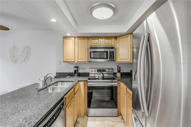 kitchen featuring light brown cabinets, a raised ceiling, sink, dark stone countertops, and stainless steel appliances