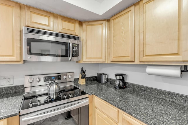 kitchen featuring light brown cabinets, dark stone countertops, and appliances with stainless steel finishes