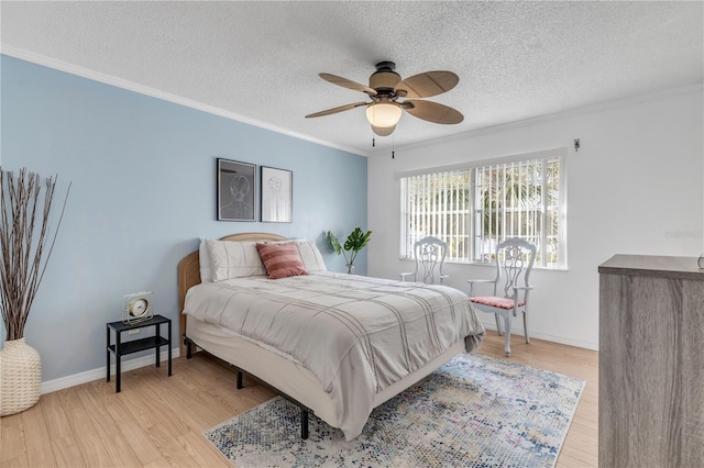 bedroom featuring ceiling fan, crown molding, a textured ceiling, and light wood-type flooring