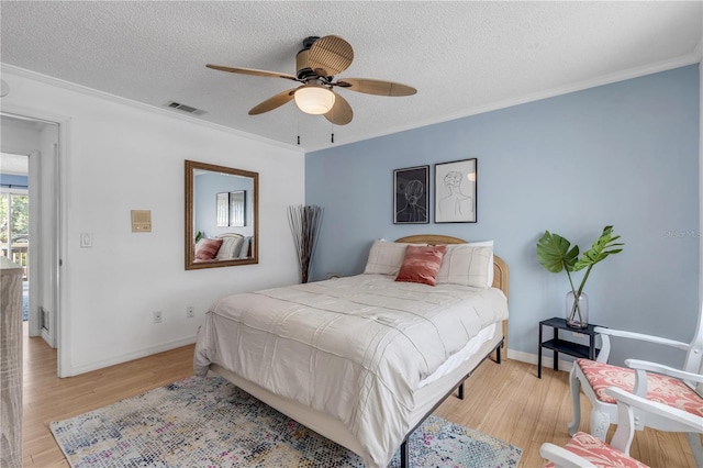 bedroom with ceiling fan, crown molding, light hardwood / wood-style floors, and a textured ceiling