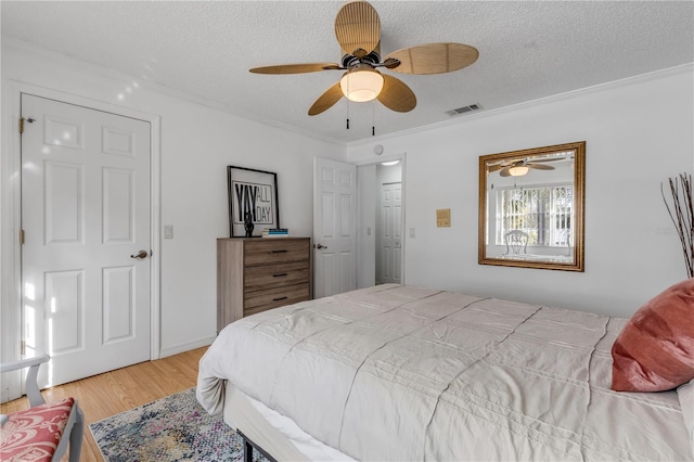 bedroom featuring hardwood / wood-style floors, ceiling fan, crown molding, and a textured ceiling