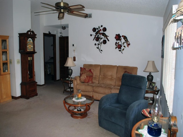 carpeted living room featuring ceiling fan and a textured ceiling