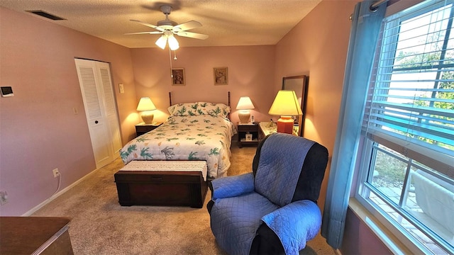 carpeted bedroom with ceiling fan, a closet, and a textured ceiling