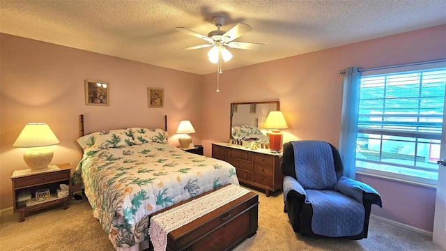 bedroom featuring a textured ceiling, light colored carpet, and ceiling fan