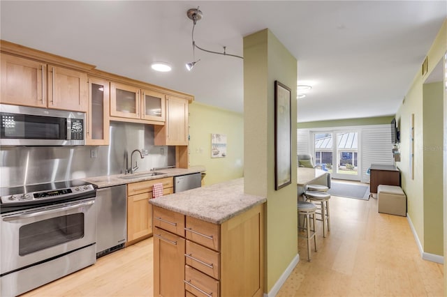 kitchen featuring light brown cabinets, sink, light hardwood / wood-style flooring, light stone countertops, and appliances with stainless steel finishes