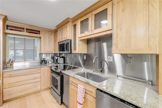 kitchen featuring light stone countertops, appliances with stainless steel finishes, light brown cabinetry, and sink