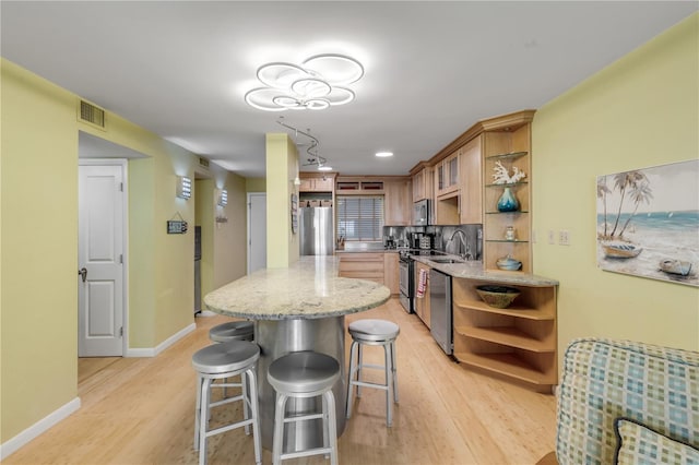 kitchen featuring decorative backsplash, light stone counters, light hardwood / wood-style flooring, and stainless steel appliances