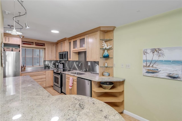 kitchen featuring sink, decorative backsplash, light stone countertops, appliances with stainless steel finishes, and decorative light fixtures