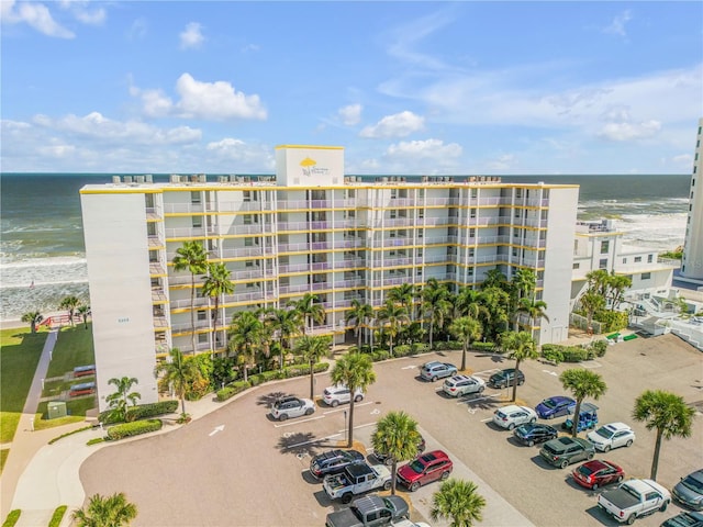 view of building exterior featuring a water view and a beach view