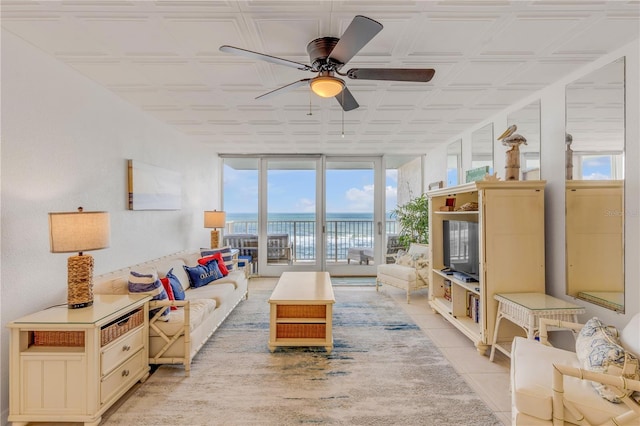 tiled living room with ceiling fan and expansive windows