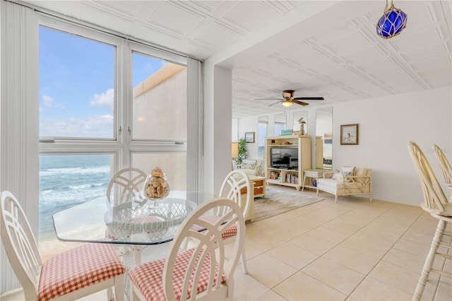 tiled dining room featuring expansive windows, ceiling fan, and a water view