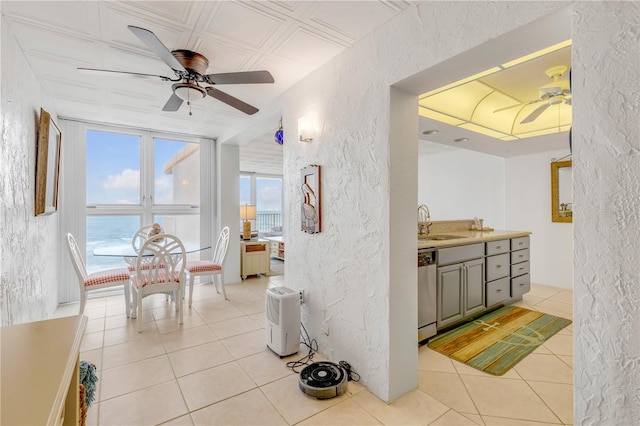 interior space with dishwasher, a water view, sink, light tile patterned flooring, and a wall of windows