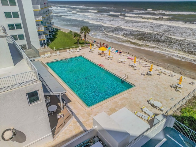 view of pool featuring a patio area, a water view, and a beach view